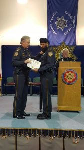 Deputy Nijjar accepts diploma from sheriff at graduation. 