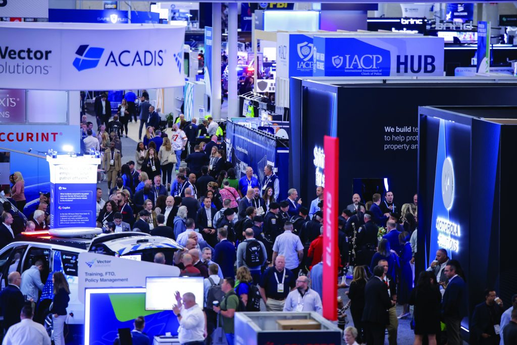 Crowded law enforcement conference floor with booths from Vector Solutions, Acadis, IACP HUB, and attendees engaging across branded displays