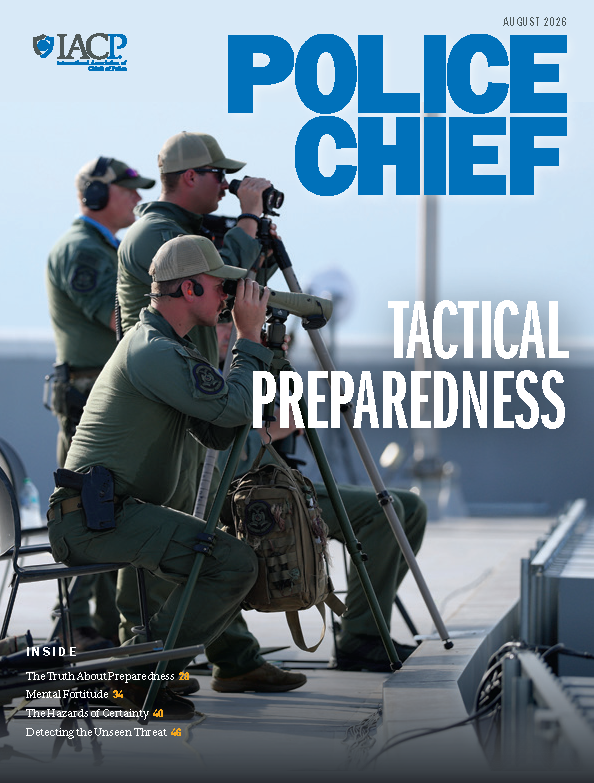 Police Chief August 2026 magazine cover features tactical observers using spotting scopes, binoculars, tripods, headsets, chairs, and gear bags on an elevated platform, with IACP branding, ‘Tactical Preparedness’ headline, and article listings against a blurred outdoor background