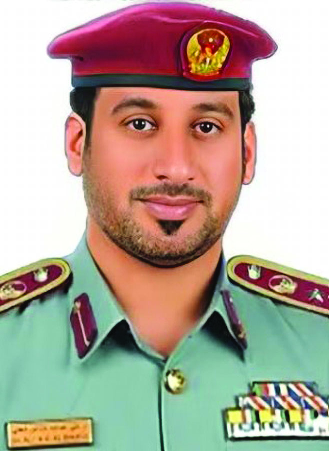Uniformed officer wearing a maroon beret with emblem, green dress uniform with gold buttons, maroon-trimmed shoulder boards, nameplate, and service ribbon