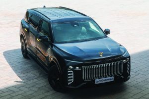Black armored SUV with bold vertical grille, gold emblem on hood, tinted windows, and LAC HỒNG 900 LX plate parked on light stone pavement