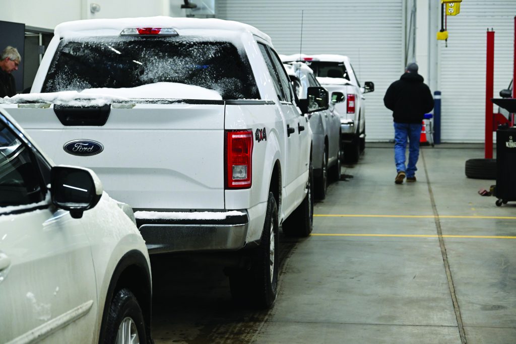A garage covered in snow, with several vehicles parked inside. The scene highlights the winter conditions and the sheltered environment provided by the garage.