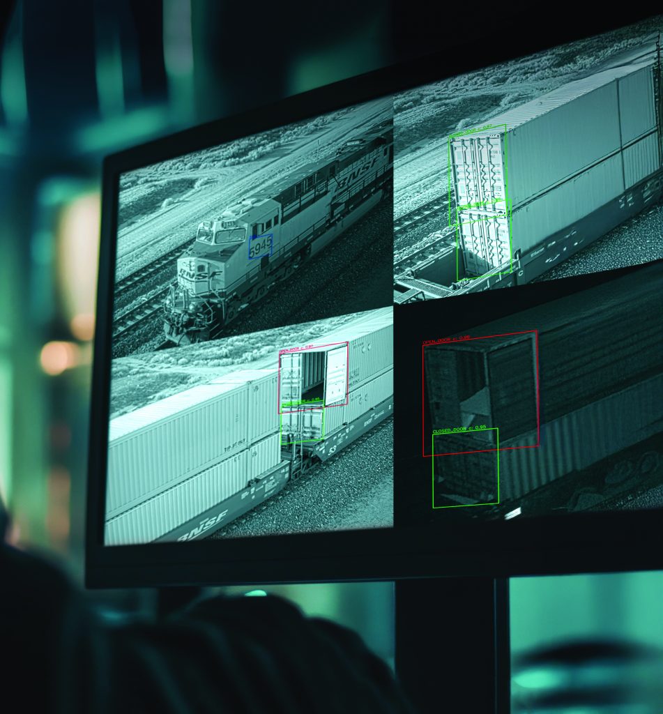 Monitor displays three black-and-white surveillance images of cargo train; red and green boxes highlight specific areas for inspection or analysis