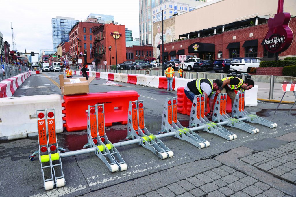 A team of community members stands behind a barrier in Arvada, Colorado, with downtown in the background.
