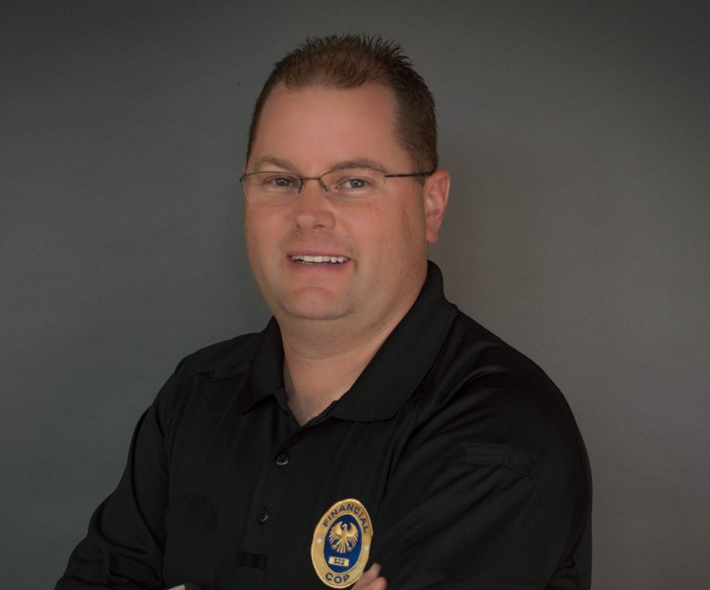 a person standing against a plain, dark gray background. The person is wearing a black polo shirt with an embroidered badge on the left side of the chest. The badge features an eagle emblem and the word "COP" prominently displayed at the bottom. The person's arms are crossed in front of their chest. The person's hair is short and neatly groomed.