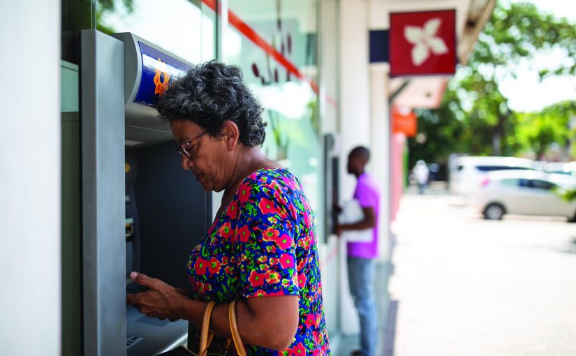 Two business‑attired figures shake hands in the foreground, overlaid with a dotted world map, with a modern city skyline and buildings visible behind