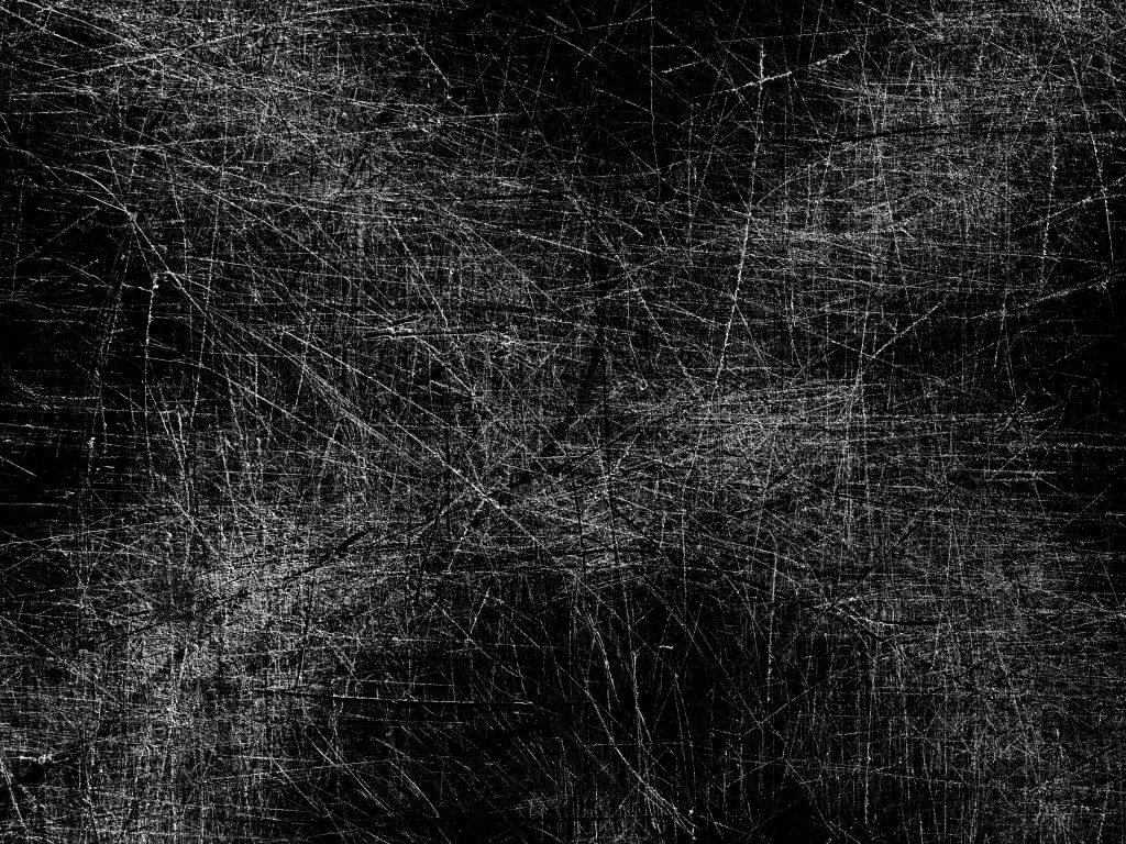 Dense white scratch lines crisscross over a black background, forming chaotic overlapping marks and rough textures that resemble worn metal surfaces throughout