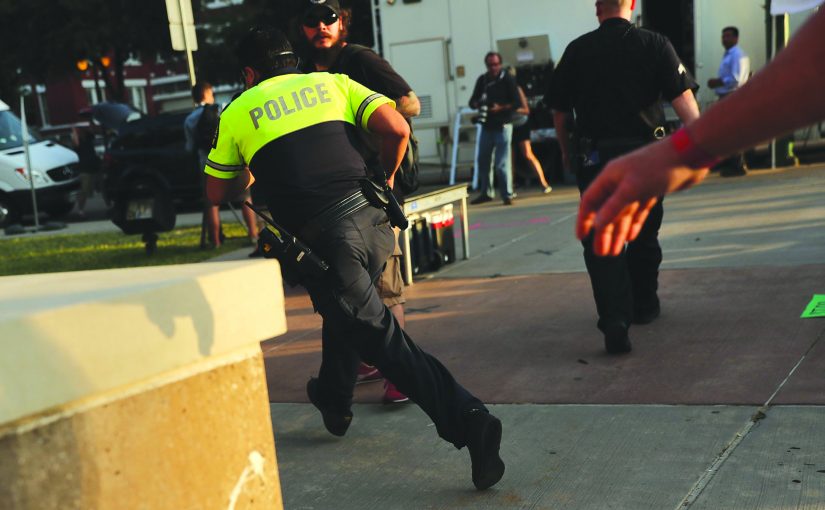 Police officer running toward a building.