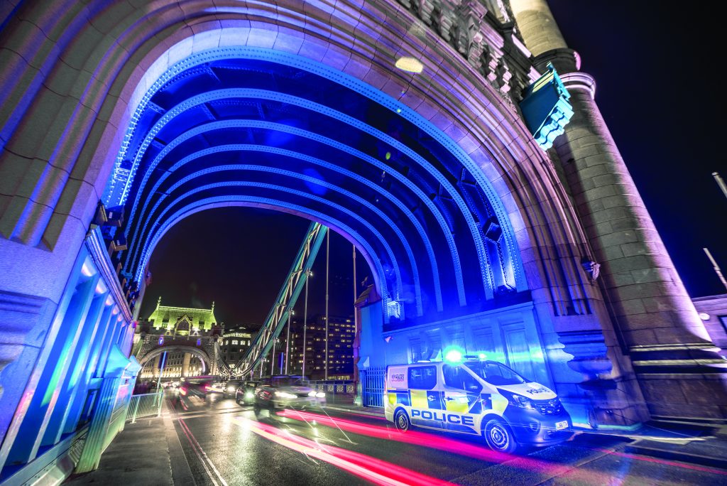 Traffic seen passing a police van on Tower Bridge (London) at night.