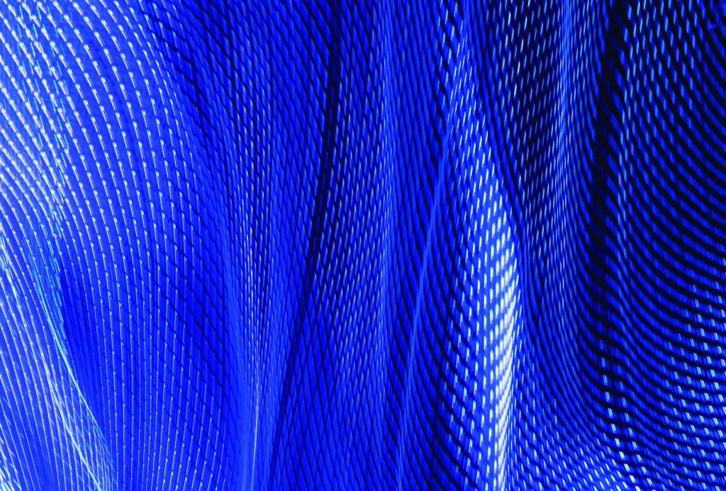 Abstract pattern of blue and white light streaks forming wavy, mesh-like structures on dark background; conveys motion, depth, and digital energy