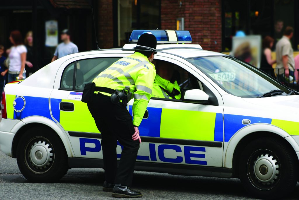 Officer bending down to talk to officer in patrol car