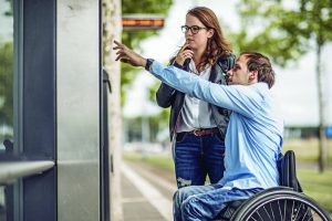 Wheelchair using young man and his girlfriend travelling around a modern city