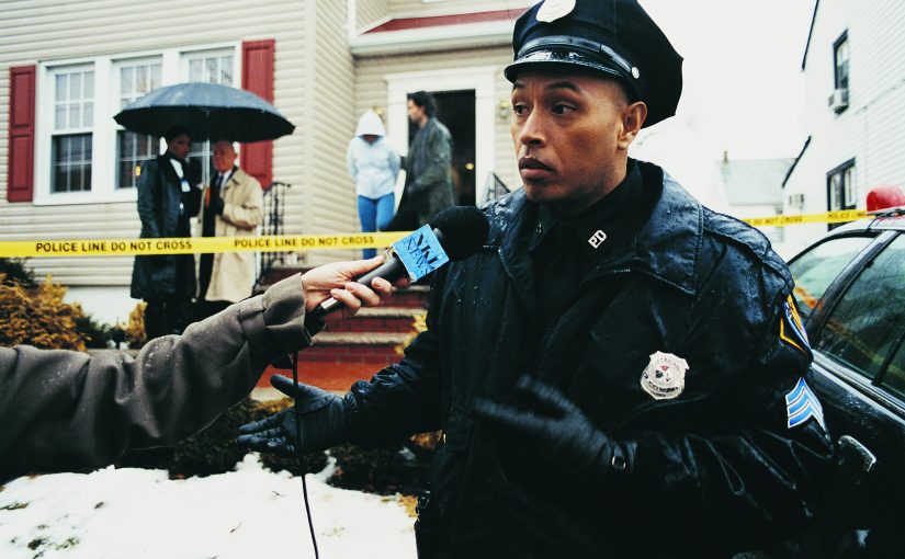 Policeman Being Interviewed by the Media on a Driveway at a Crime Scene