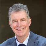 Portrait of a police officer in uniform, smiling and standing in front of a backdrop
