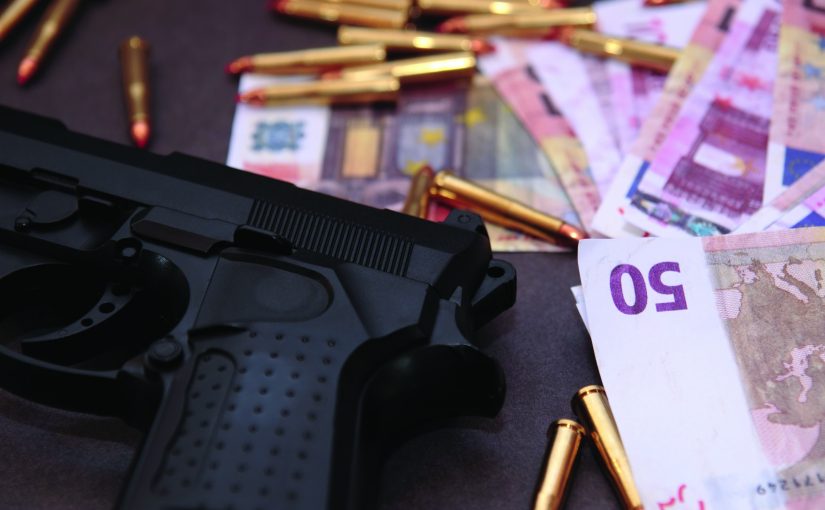 Image of gun, bullet casings, and international cash