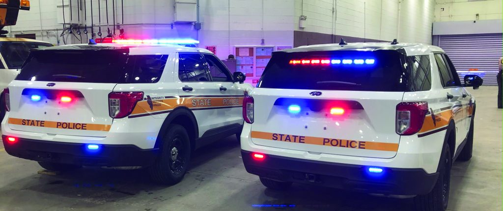 Police SUV vehicle with all real patrol lights on with a bar of lights on the top of the rear windshield, two above the license plate, and two under the rear boot