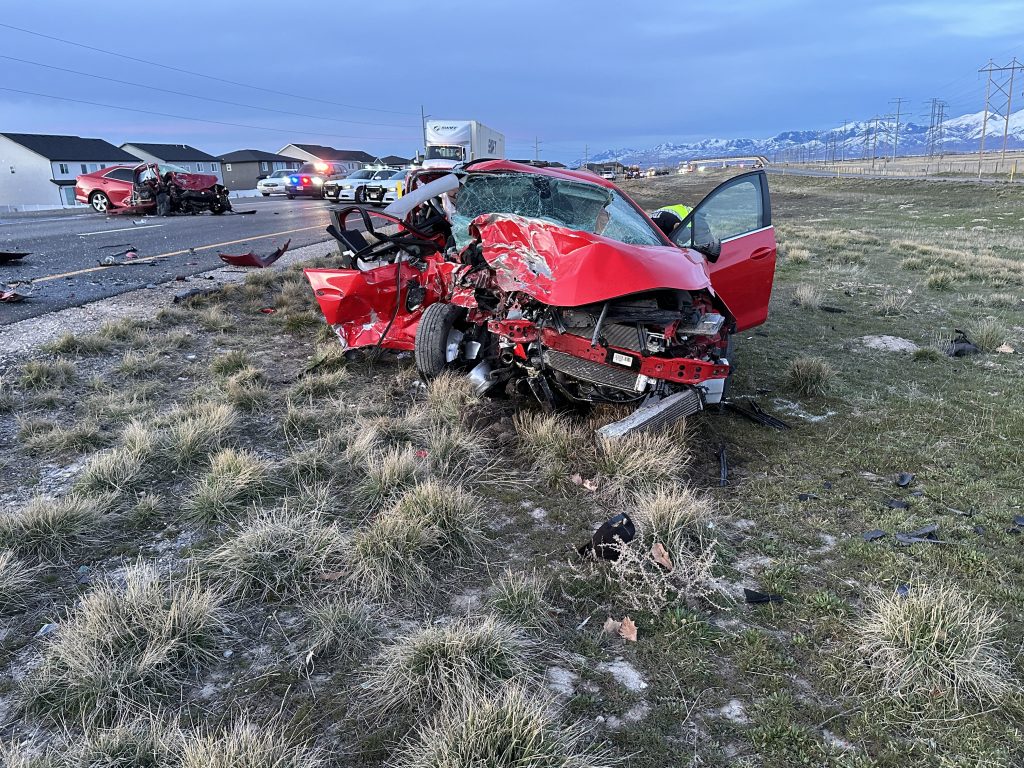 Red car on the side of the road with major damage to the passenger side