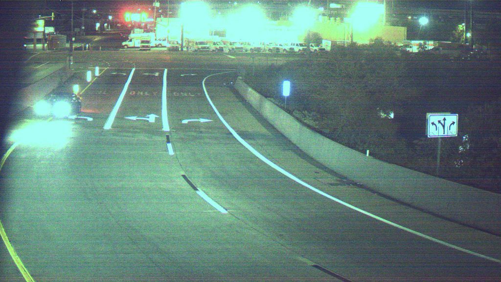 The view from a traffic camera showing a car driving on the wrong side of the road on a exit ramp