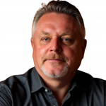 Studio portrait shows an individual with short combed hair wearing a dark button‑down shirt, photographed against a plain white background with even lighting