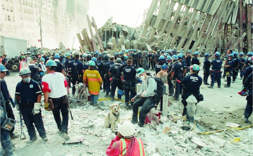 World Trade Center recovery site filled with responders in helmets, respirators, uniforms, and safety gear amid collapsed steel, concrete debris, dust, rescue equipment, a search dog, fire hydrant, recovery tools, and heavily damaged structural remains