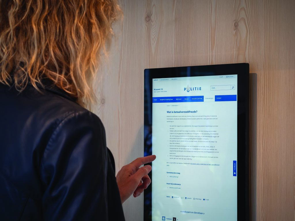 A police officer from Utrecht standing in front of a modern building, equipped with tactical gear. The officer is engaged in a public safety operation, highlighting the readiness and professionalism of the police force