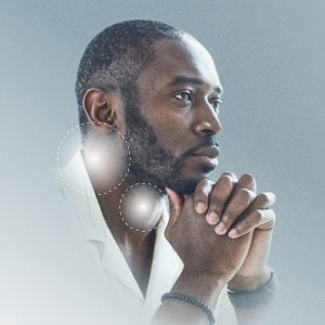 A man with short hair is seen in profile, facing left. He is wearing a white shirt and has his hands clasped together near his chin. There are two glowing circles near his ear, connected by dotted lines, giving the image a futuristic or technological feel. The background is a gradient of light blue to white.